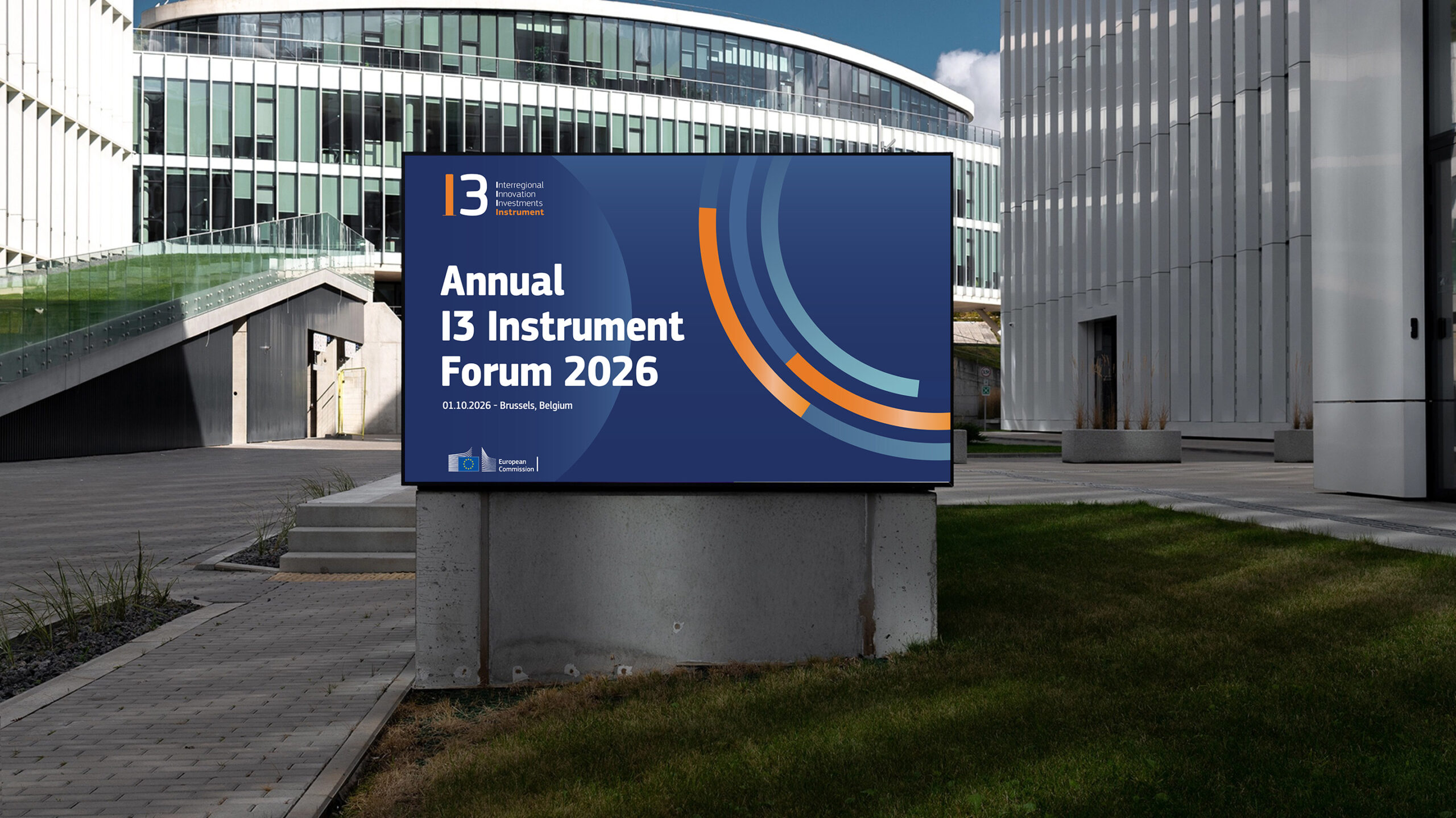 Annual I3 Forum 2026 visual displayed on an outdoor digital screen in front of a modern glass building, featuring the I3 logo and brand colors on a navy background.